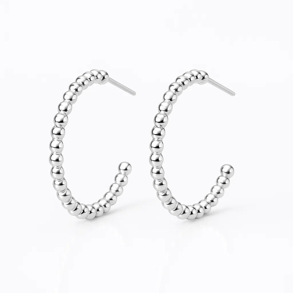 Silver beaded hoop earrings on a white background