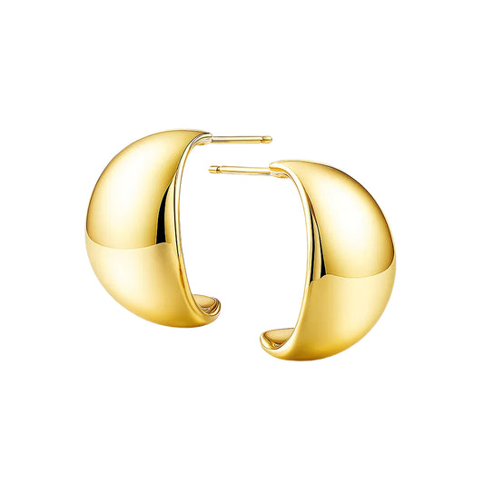 Gold hoop earrings on a reflective surface with a light background
